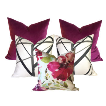 5 decorative pillows orchid velvet Channels ebony with abstract black stripes on white linen and a pink floral pillow in the front, all against a white background