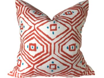 pass a grille white pillow with coral diamond designs with teal dots on a white background