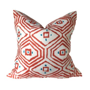 pass a grille white pillow with coral diamond designs with teal dots on a white background